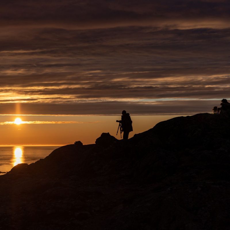 silhouette of a photographer who captures the image of the midnight sun at Sommaroy (Sommarøy), Tromso Norway